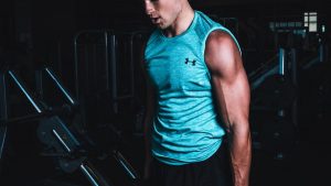 Man exercising indoors, lifting dumbbells for strength training in a Towson gym.